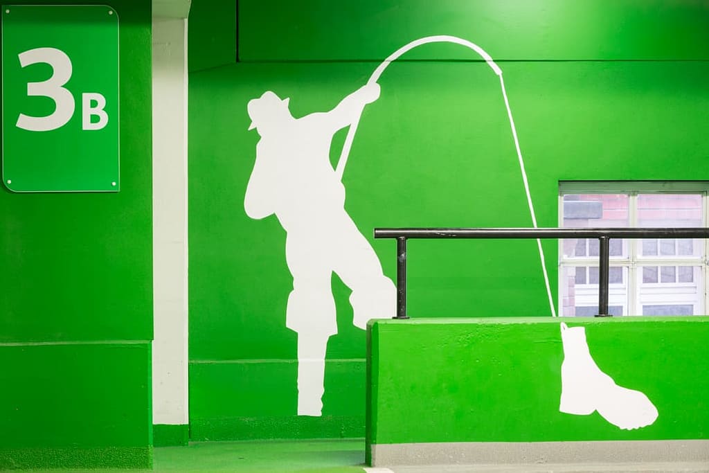 Large supergraphic with a white graphic of a fisherman with an old boot on the end of his line. This is one a bright green background.