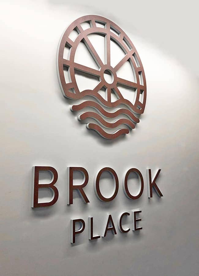 Identity sign designed for the reception for Brook Place Apartments, Sheffield, featuring individual built up letters of the building name and logo faced in a corten steel laminate
