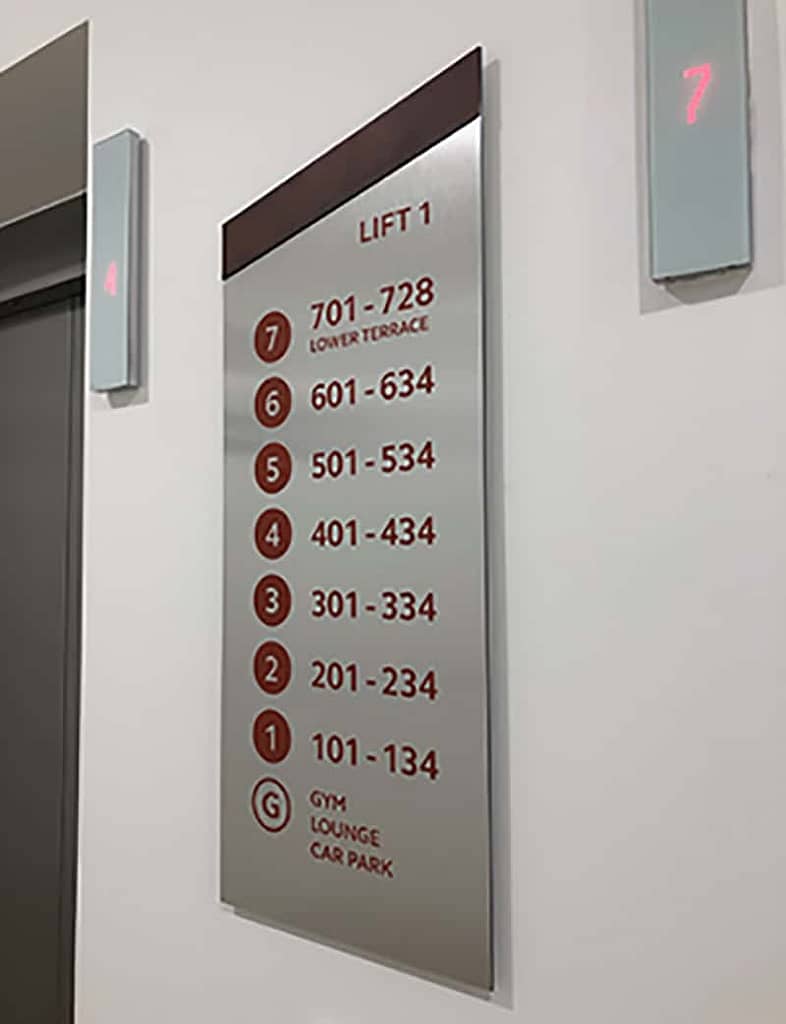 Lift index sign designed for Brook Place Apartments, featuring corten steel vinyl letters on a brushed stainless steel, mono-pitched shape sign